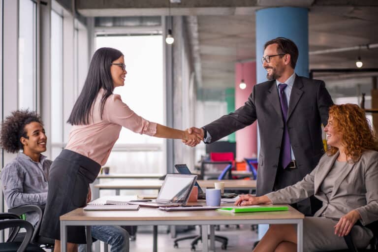 people negotiating shaking hands over table