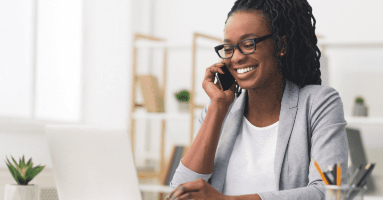 Young sales person making prospecting calls wearing gray sitting in their office with laptop open and pens in a cup holder