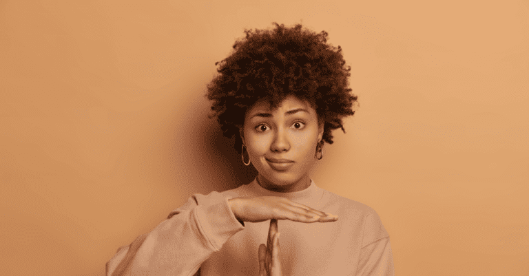 Salesperson making a T with their hands to call for a pause in the sales process in front of an orange background