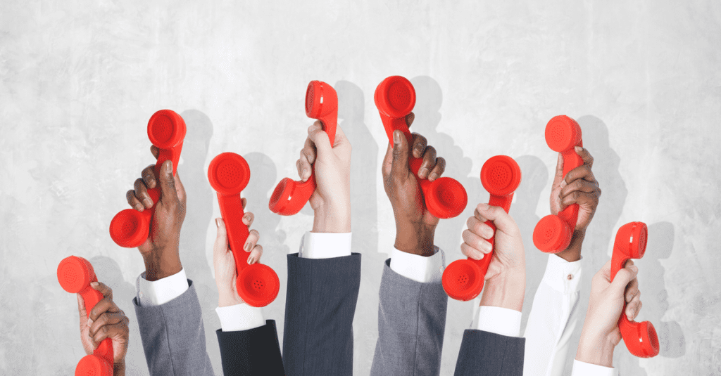 Eight sales people in suits holding up red phones in front of a gray background making prospecting calls