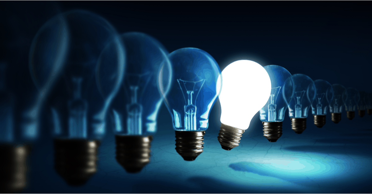 Eleven lightbulbs in a row with one in the middle lit and tilted slightly forward on a dark deep blue background