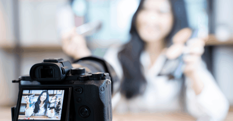 Video camera in focus at the bottom left filiming a video testimonial with the person being filmed out of focus