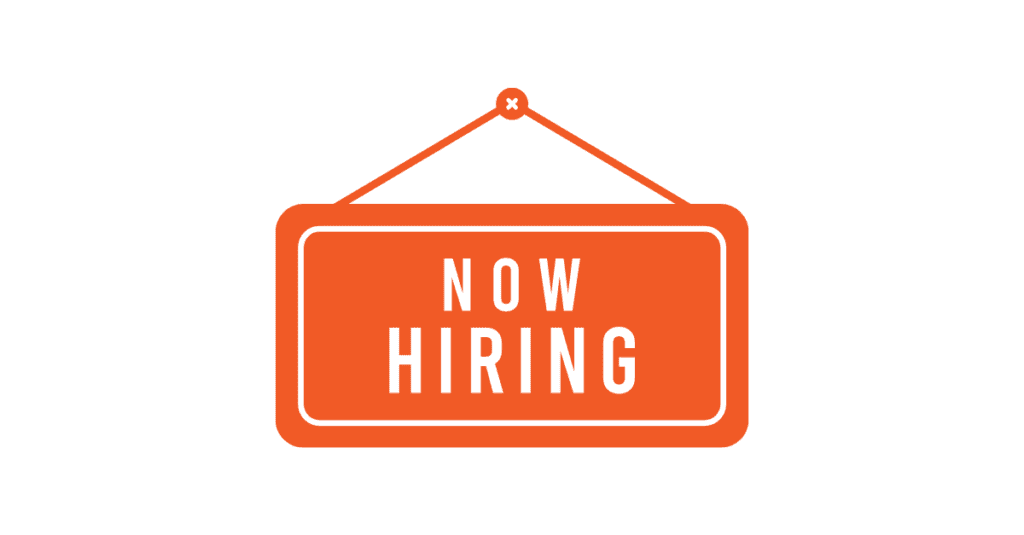 Small business owner reviewing a Now Hiring sign — free Sales Gravy guide to hiring salespeople for small business